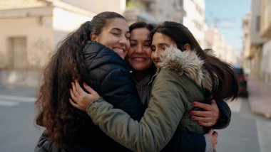 Mother and daugthers smiling confident hugging each other at street