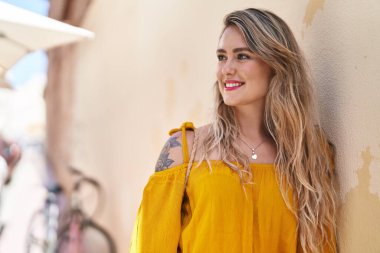 Gülümseyen genç bir kadın sokağın kenarına bakıyor kendinden emin.