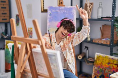 Genç İspanyol ressam resim stüdyosunda müzik dinliyor.