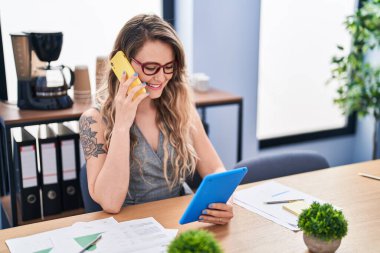 Ofiste akıllı telefondan konuşan genç bir iş kadını dokunmatik ped kullanıyor.