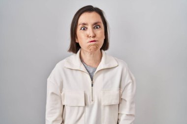 Middle age hispanic woman standing over isolated background puffing cheeks with funny face. mouth inflated with air, crazy expression. 