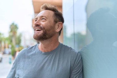 Middle age man smiling confident looking to the side at street