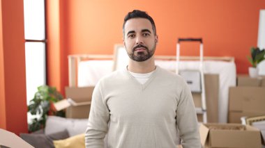 Young hispanic man standing with relaxed expression at new home