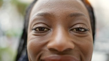 Sokakta kendinden emin gülümseyen Afrikalı Amerikalı kadın.