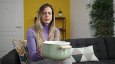 Evde su sızıntısı için tencere tutan genç sarışın kadın.