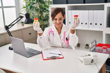 Middle age woman wearing doctor uniform holding urine analysis test tubes at clinic