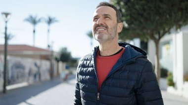 Middle age man smiling confident looking to the sky at street