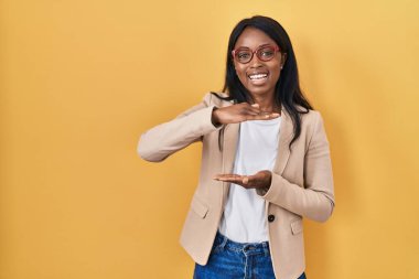 Elleriyle işaret eden gözlüklü Afrikalı genç bir kadın büyük ve büyük bir işaret, ölçü sembolü gösteriyor. Kameraya bakıp gülümsüyor. ölçüm kavramı. 