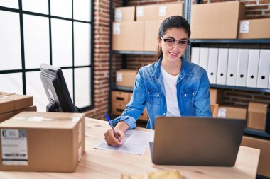 Genç ve güzel İspanyol kadın, iş kadını. Ofisteki evraklarda dizüstü bilgisayar kullanıyor.