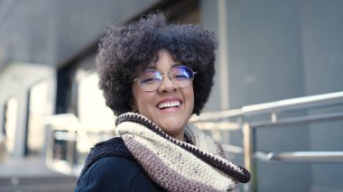 Sokakta kendinden emin gülümseyen Afrikalı Amerikalı genç bir kadın.