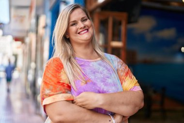 Young woman smiling confident standing with arms crossed gesture at street