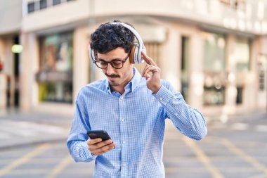 Young caucasian man listening to music at street
