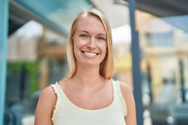 Sokakta kendine güvenen genç sarışın kadın gülümsüyor