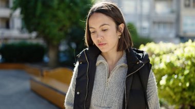 Parkta ciddi bir ifadeyle duran genç, güzel İspanyol kadın.