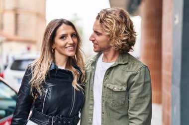 Erkek ve kadın bir arada durarak gülümsüyor.