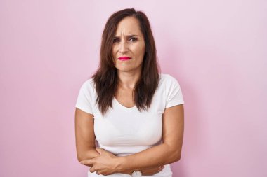 Orta yaşlı esmer kadın, midesi üstünde pembe arka planda duruyor çünkü hazımsızlık, acı verici bir hastalık kendini iyi hissetmiyor. Ağrı kavramı. 
