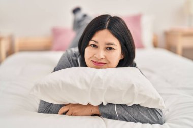 Young chinese woman smiling confident lying on bed at bedroom