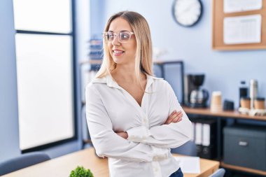 Young woman business worker standing with arms crossed gesture at office
