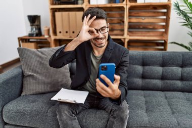 Genç İspanyol psikolog akıllı telefonuyla terapi yapıyor mutlu bir şekilde gülümsüyor. El ele imzala ve parmaklarından bak. 