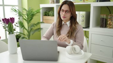 Evdeki masada dizüstü bilgisayar kullanan güzel bir İspanyol kadın.