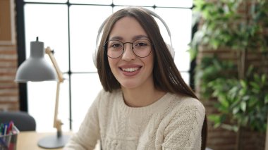 Young beautiful hispanic woman business worker listening to music at office