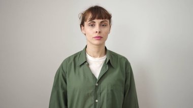 İzole edilmiş beyaz arka planda ciddi bir ifadeyle duran beyaz bir kadın.