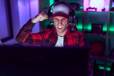 Video oyunları oynayan genç beyaz adam öfkeyle bağırıyor, öfkeyle bağırıyor ve el kaldırıyor. 