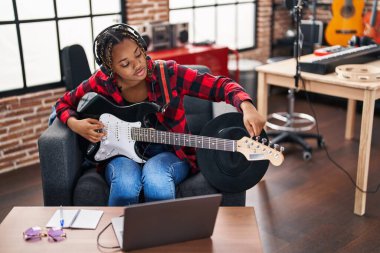 Afrikalı Amerikalı kadın müzisyen müzik stüdyosunda elektronik gitar dersi alıyor.