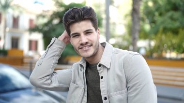 Parkta kendinden emin gülümseyen İspanyol genç adam.