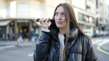 Genç ve güzel İspanyol kadın gülümsüyor. Caddedeki akıllı telefondan kendine güvenen bir sesli mesaj dinliyor.