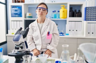 Down sendromlu İspanyol kız bilim adamı laboratuarında çalışıyor kameraya bakıp havada öpücük yolluyor ve sevimli ve seksi oluyor. aşk ifadesi. 