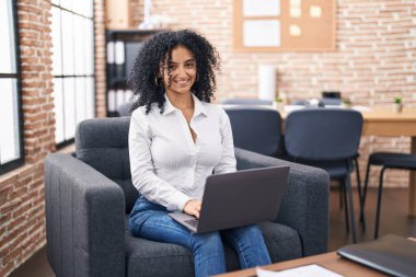 Ofiste çalışan genç İspanyol iş kadını laptopu kullanıyor.