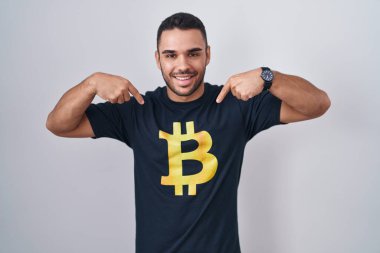 Bitcoin tişört giyen genç İspanyol adam. Kendine güvenen, yüzünde gülümseme olan, kendini gururlu ve mutlu gösteren.. 