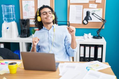 Genç Latin iş adamı ofiste müzik dinliyor.
