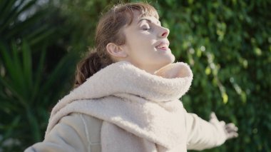 Young caucasian woman smiling confident with closed eyes enjoying sunlight at park