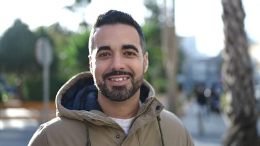 Parkta kendinden emin gülümseyen İspanyol genç adam.