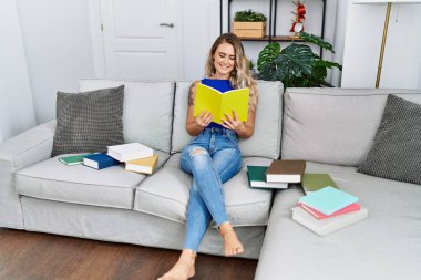 Kanepede oturan genç bayan evde ders çalışıyor.