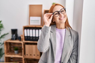 Kafkasyalı genç bir iş kadını ofiste kendinden emin gülümsüyor.