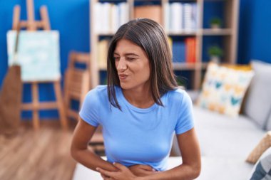 Mide bulantısı, acı verici bir hastalık yüzünden evdeki koltukta oturan esmer bir genç kadın. Ağrı kavramı. 