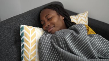 African woman lying on sofa sleeping at home