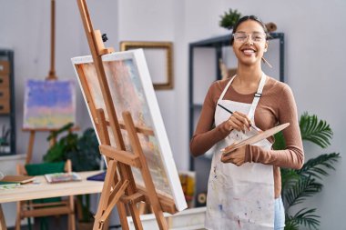 Genç Afrikalı Amerikalı kadın sanatçı sanat stüdyosunda kendine güvenen bir çizim yapıyor.