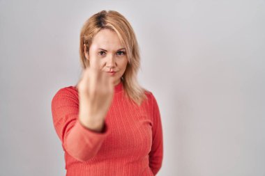 Blonde woman standing over isolated background showing middle finger, impolite and rude fuck off expression 