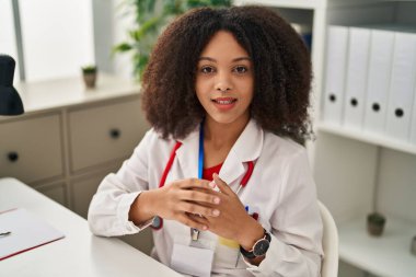 Young african american woman wearing doctor uniform speaking at clinic