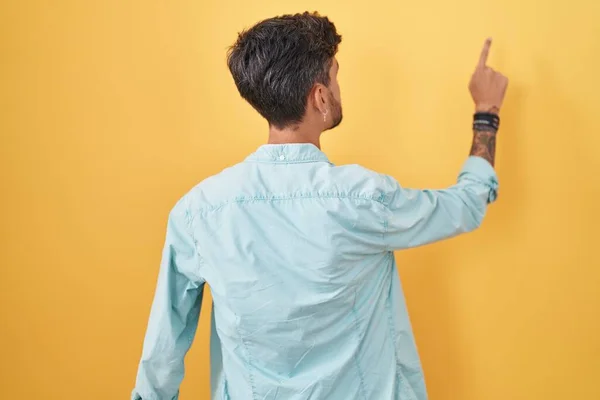 Young Hispanic Man Tattoos Standing Yellow Background Posing Backwards Pointing — стоковое фото