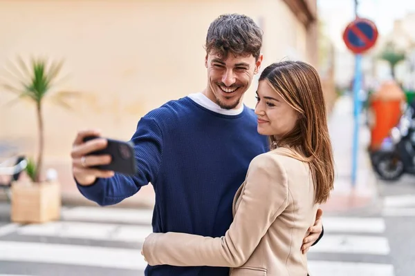 男性と女性のカップル抱擁お互いに作る自撮りによってスマートフォンでストリート — ストック写真