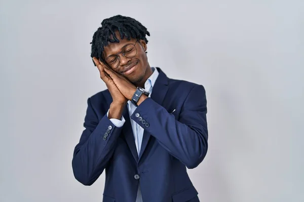 Young african man with dreadlocks wearing business jacket over white background sleeping tired dreaming and posing with hands together while smiling with closed eyes.