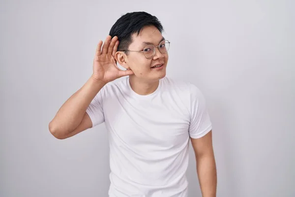 Beyaz Arka Planda Dikilen Asyalı Genç Adam Kulağına Fısıldayarak Dedikoduları — Stok fotoğraf