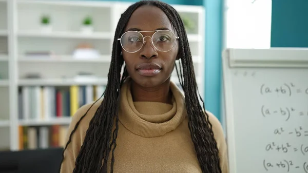 stock image African woman standing with serious expression wearing glasses at library university