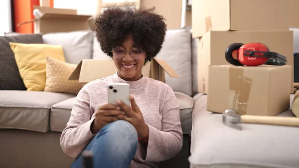 Genç Afrikalı Amerikalı Kadın Yeni Evinde Akıllı Telefon Kullanarak Gülümsüyor — Stok fotoğraf
