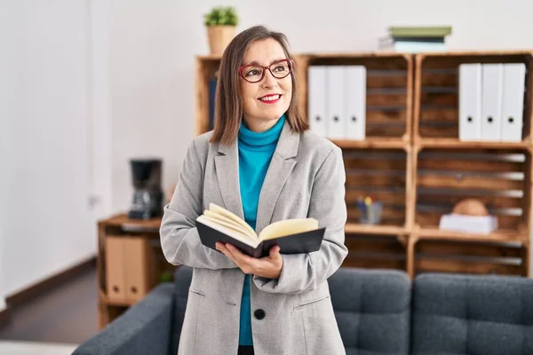 stock image Middle age woman psychologist smiling confident reading book at psychology center